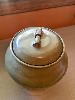 Vintage sage green ceramic pottery with a detailed lid and handle, top view of the glazed pot.